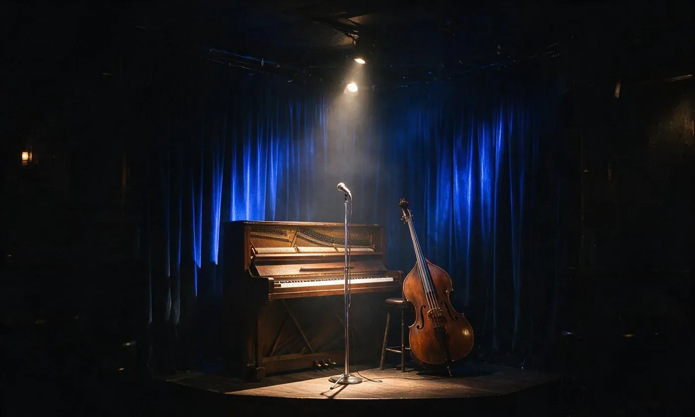 The small stage at Velvet Hour: an upright piano, a microphone stand and a double bass in front of a midnight-blue curtain, lit by one spotlight.